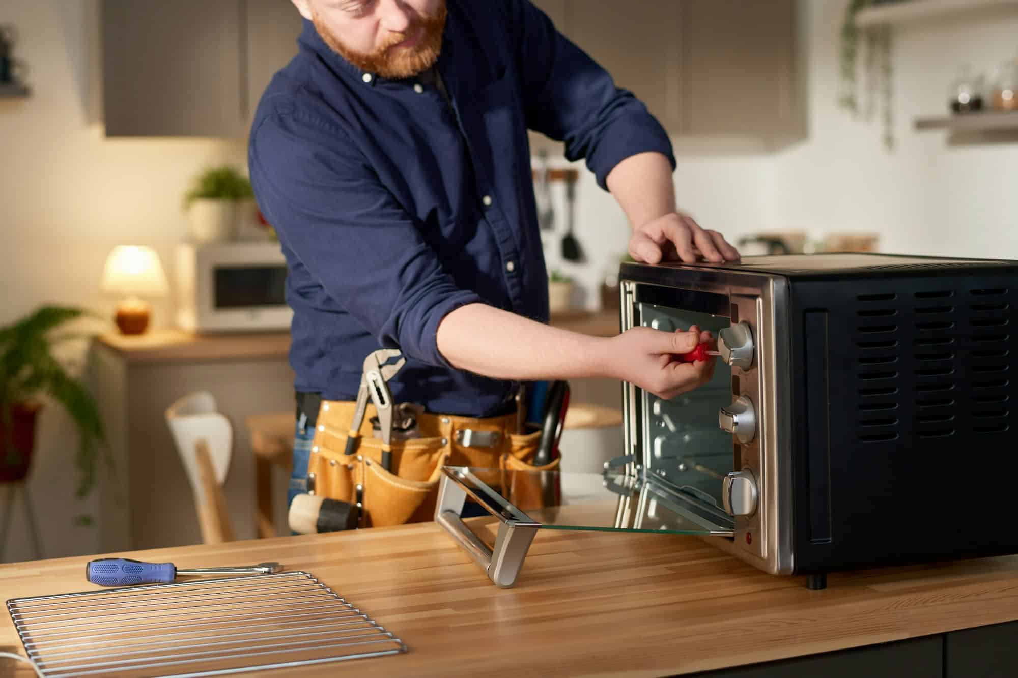 repairman-using-tools-to-fix-microwave